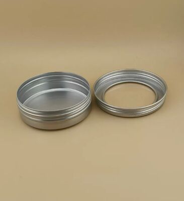 Une grande étui en aluminium argenté avec un bouchon à vis transparent pour les cosmétiques