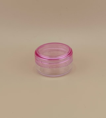 Un pot de crème en plastique transparent certifié avec un couvercle à vis rose pour les soins de la peau et personnalisable